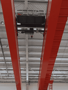 Overhead view of a red steel crane beam inside a warehouse, illustrating heavy-duty support and industrial functionality.