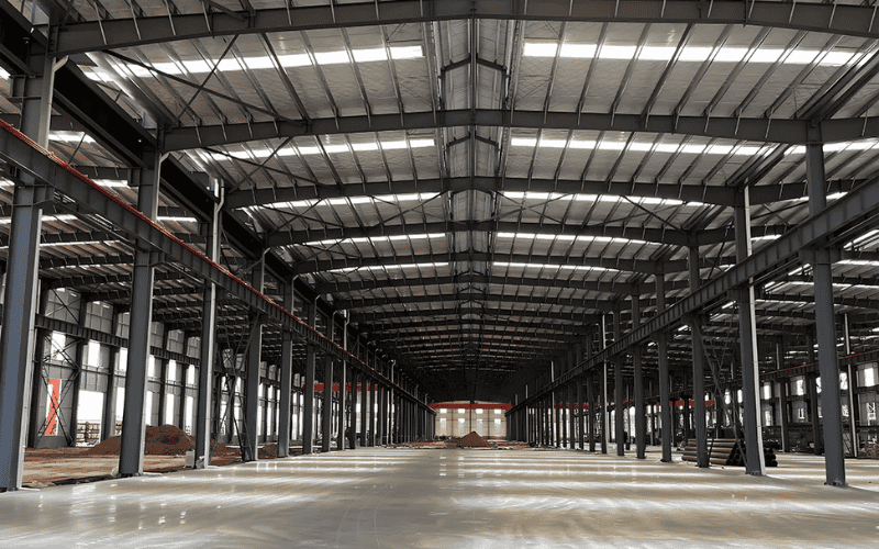 Interior view of a large steel-framed industrial warehouse with high ceilings and spacious floor area.