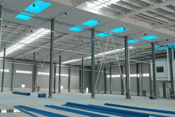 A spacious industrial workshop with steel pillars and beams, featuring skylights that let in natural light.