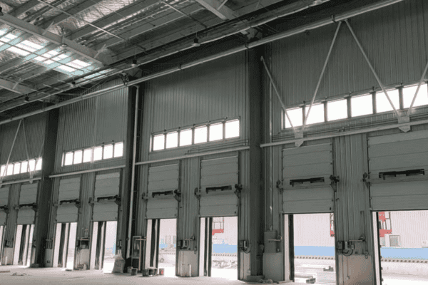 Interior view of a logistics facility with multiple loading docks and roll-up doors under bright lighting.